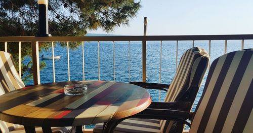 Empty chairs and tables at restaurant against sea