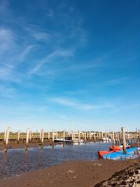 Sailboats moored on beach against blue sky