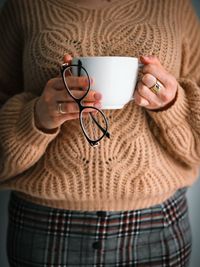 Midsection of woman holding coffee on table