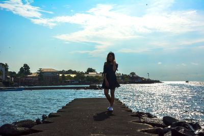 Full length of woman standing at beach against sky