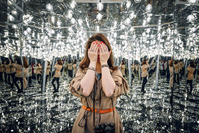 Woman covering eyes in mirror maze