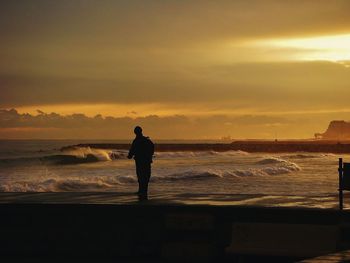 Silhouette of people on beach at sunset