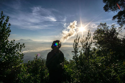 Man standing by tree against sky