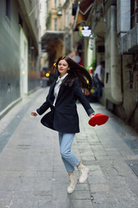 Portrait of young woman walking on street in city