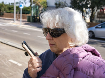 Mature woman with white hair and sunglasses talking on the phone.