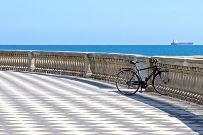 Bicycle by sea against sky