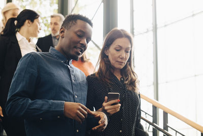 Colleagues talking while moving down steps by window at office