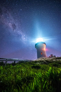 Lighthouse on field against sky at night