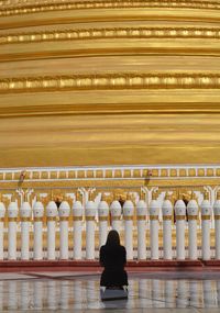 Rear view of woman praying while looking at mosque