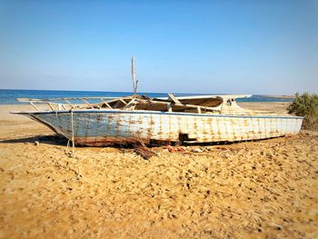 Abandoned boat on beach against clear sky