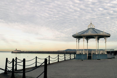 Pier on sea against cloudy sky