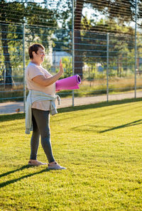 Full length of young woman exercising on field