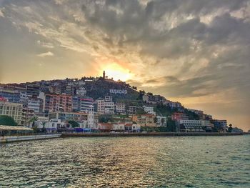 Houses by sea against sky during sunset