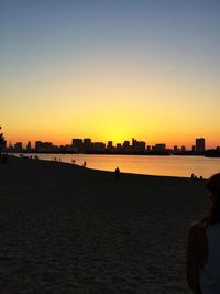 Silhouette man on beach against clear sky during sunset