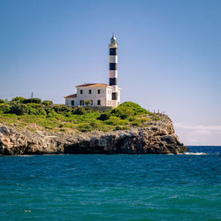 Lighthouse amidst sea and buildings against sky