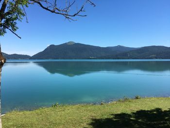 Scenic view of lake and mountains against clear blue sky