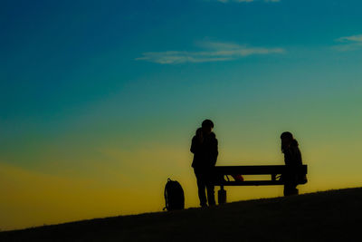 Silhouette men on field against sky during sunset