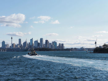 Sea by buildings in city against sky