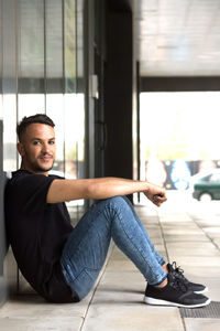 Portrait of handsome man sitting by wall