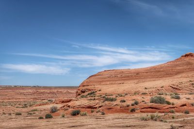 Landscape of large smooth orange rock formation or hill and a few desert plants in page, arizona