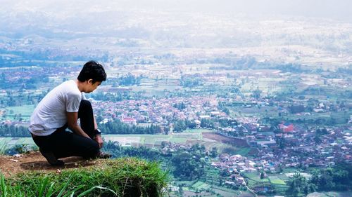 Young woman sitting on mountain against sky