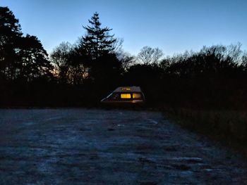 Caravan by trees on road against sky