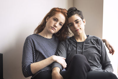 Portrait of lesbian couple sitting on chair at home