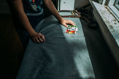 Young child lining up toy cars in a pocket of sunlight near window