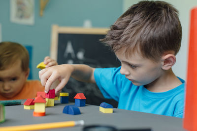 Siblings playing with toy blocks at table