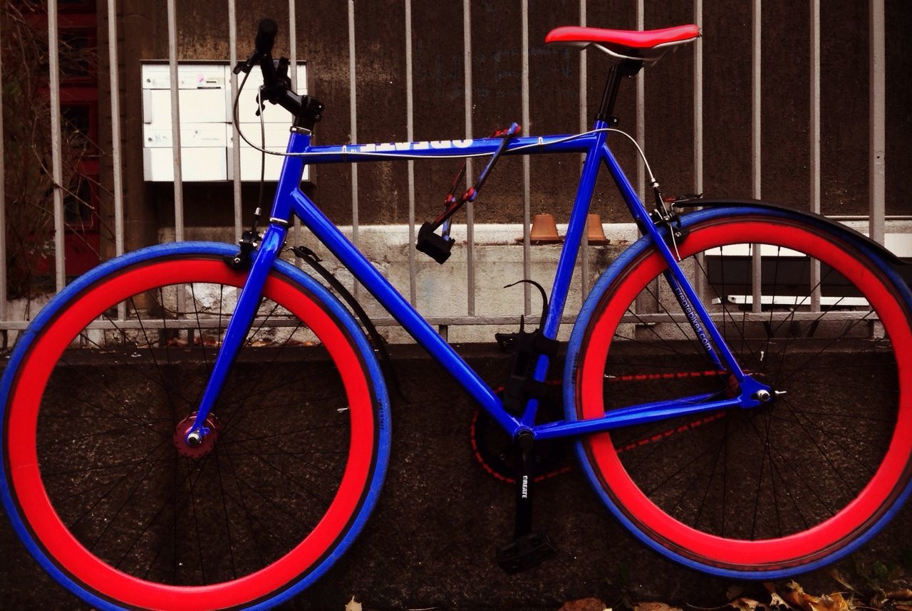 metal, red, built structure, bicycle, architecture, building exterior, close-up, wall - building feature, metallic, day, wheel, no people, railing, stationary, outdoors, circle, transportation, safety, protection, parking