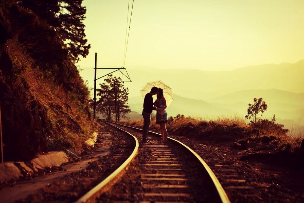 REAR VIEW OF PEOPLE ON RAILWAY TRACKS AGAINST CLEAR SKY