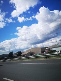 Road by buildings against sky in city