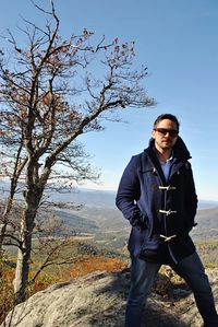 Portrait of man standing by tree against sky