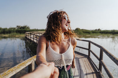 Beautiful woman standing on pier over lake against sky