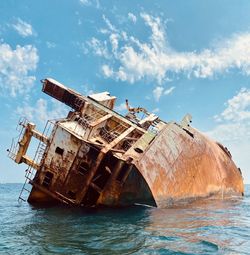 View of abandoned ship in sea against sky