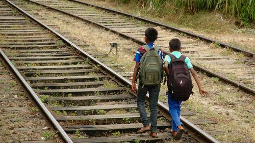 Rear view of people walking on railroad track