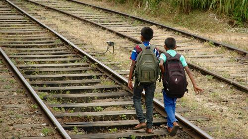 Two boys going walking on the railroad tracks on their way to school
