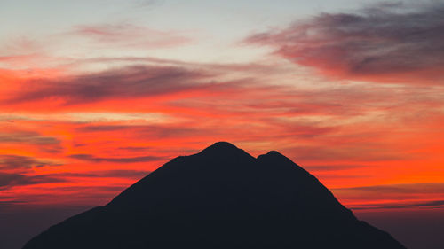 Silhouette mountain against dramatic sky during sunset