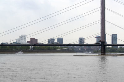 Bridge over river against sky in city