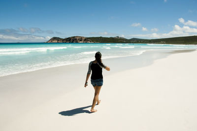 Rear view of woman on beach against sky