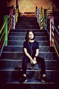 Full length portrait of woman sitting on staircase