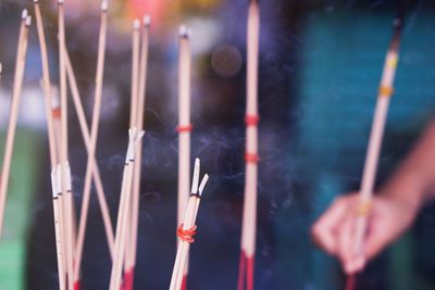 Close-up of hand holding incense sticks 
