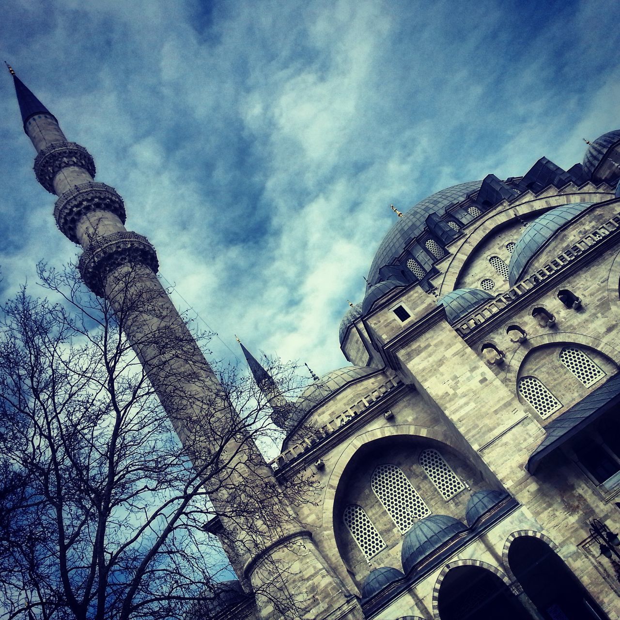 low angle view, architecture, sky, religion, building exterior, built structure, place of worship, cloud - sky, spirituality, tower, church, history, famous place, travel destinations, cloud, cloudy, tree, tourism