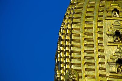 Low angle view of yellow building against clear blue sky