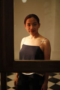 Young woman standing by glass on floor