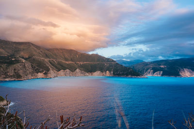 Scenic view of sea by mountains against sky