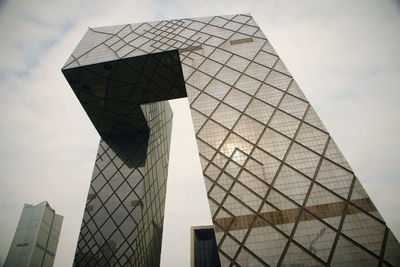 Low angle view of skyscrapers against cloudy sky