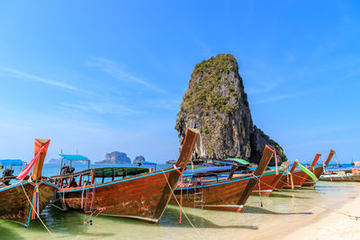 Fishing boats moored on beach against blue sky