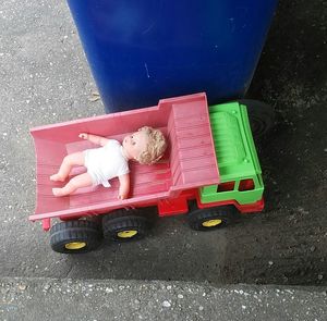 High angle view of doll on toy car by garbage bin at road