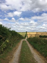 Road amidst field against sky